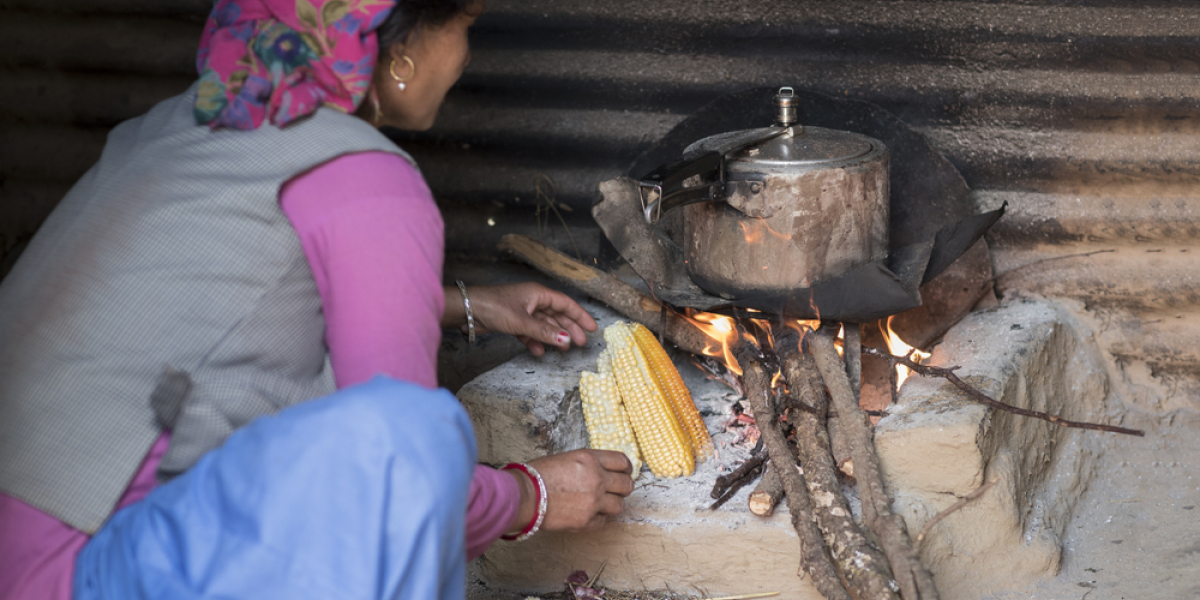 Himachali woman cooking food on wood fire stovein her kitchen, Himachal Pradesh, India.